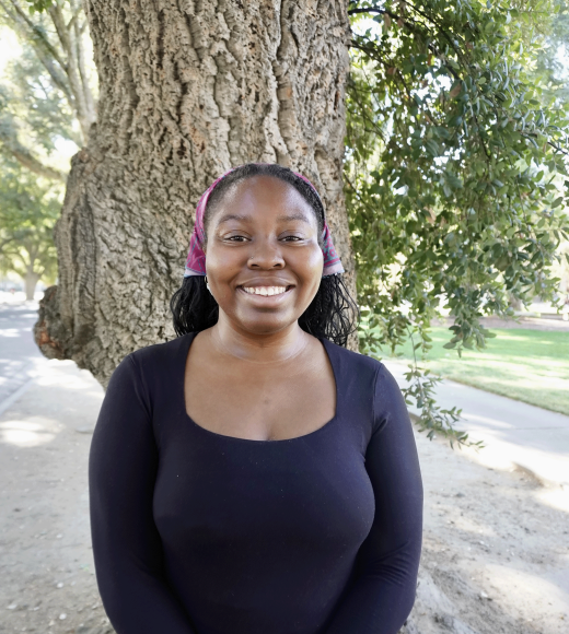 A woman in a black top standing in front of a tree