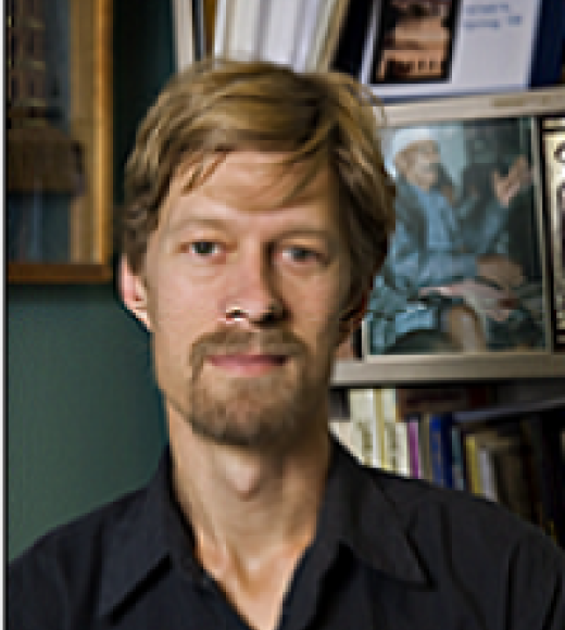 Man with goatee standing in front of a bookcase