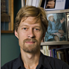 Man with goatee standing in front of a bookcase